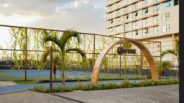 Entrada do Beach 'n Garden ao pôr do sol, com quadras de areia ao fundo